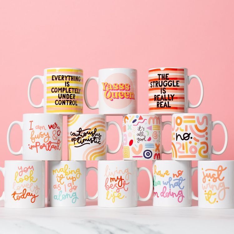 Collection of colorful mugs with various phrases on a pink background