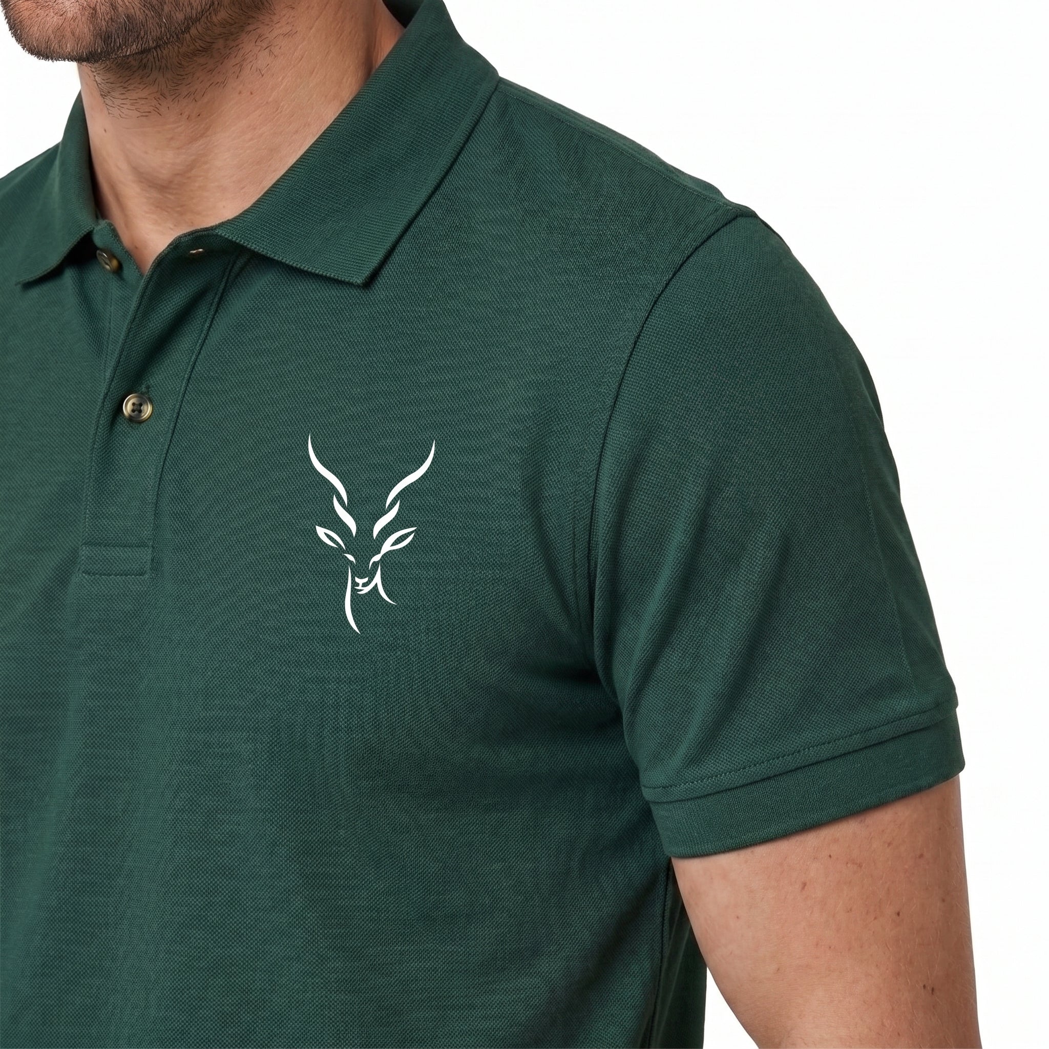 A close-up of a man wearing a dark green short-sleeve polo shirt with a white stylized antelope or deer head logo on the left chest, set against a plain white background.
