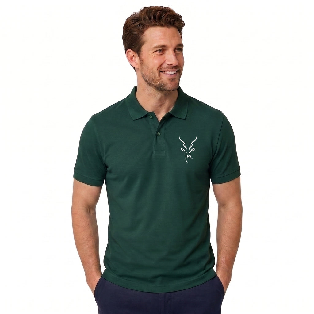 A man wearing a dark green short-sleeve polo shirt with a small white embroidered antelope logo on the left chest, paired with navy pants, against a plain white background.
