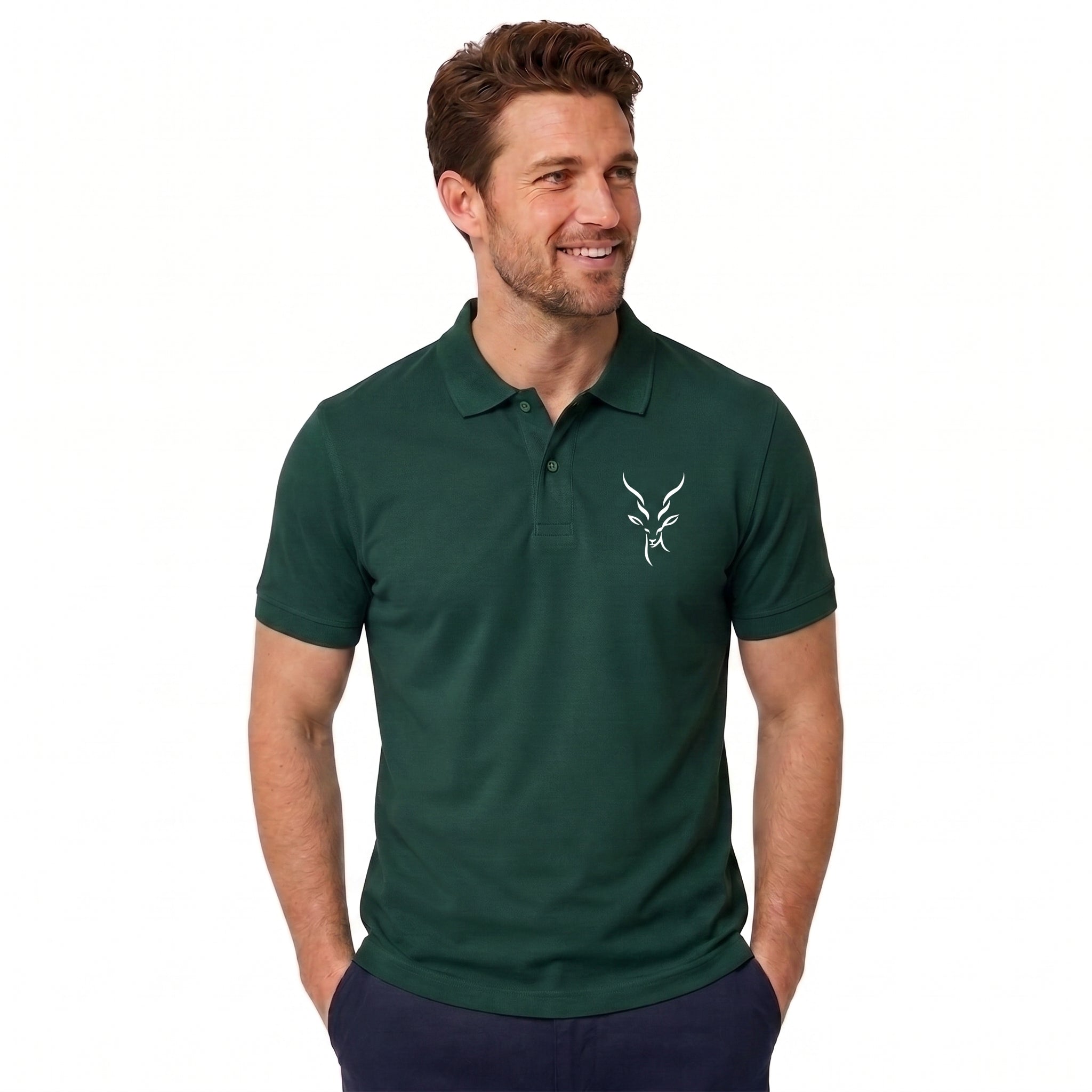 A man wearing a dark green short-sleeve polo shirt with a small white embroidered antelope logo on the left chest, paired with navy pants, against a plain white background.