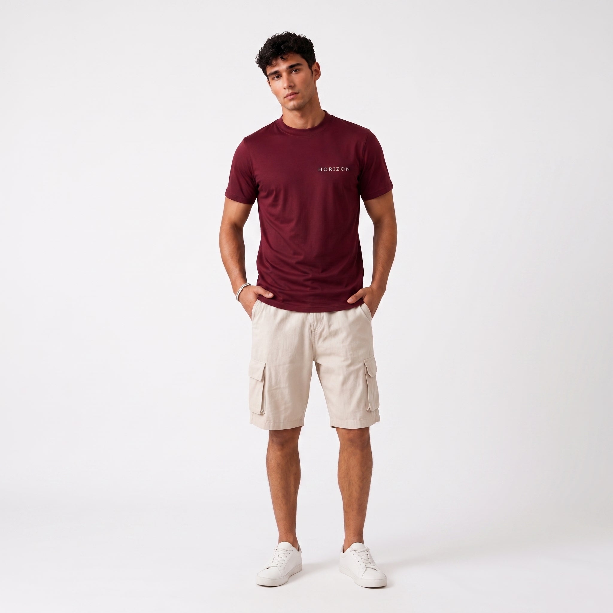 A man modeling a burgundy short-sleeve t-shirt with a small white 'HERR&WEISE' logo on the chest, paired with beige cargo shorts and white sneakers, against a plain white studio background.