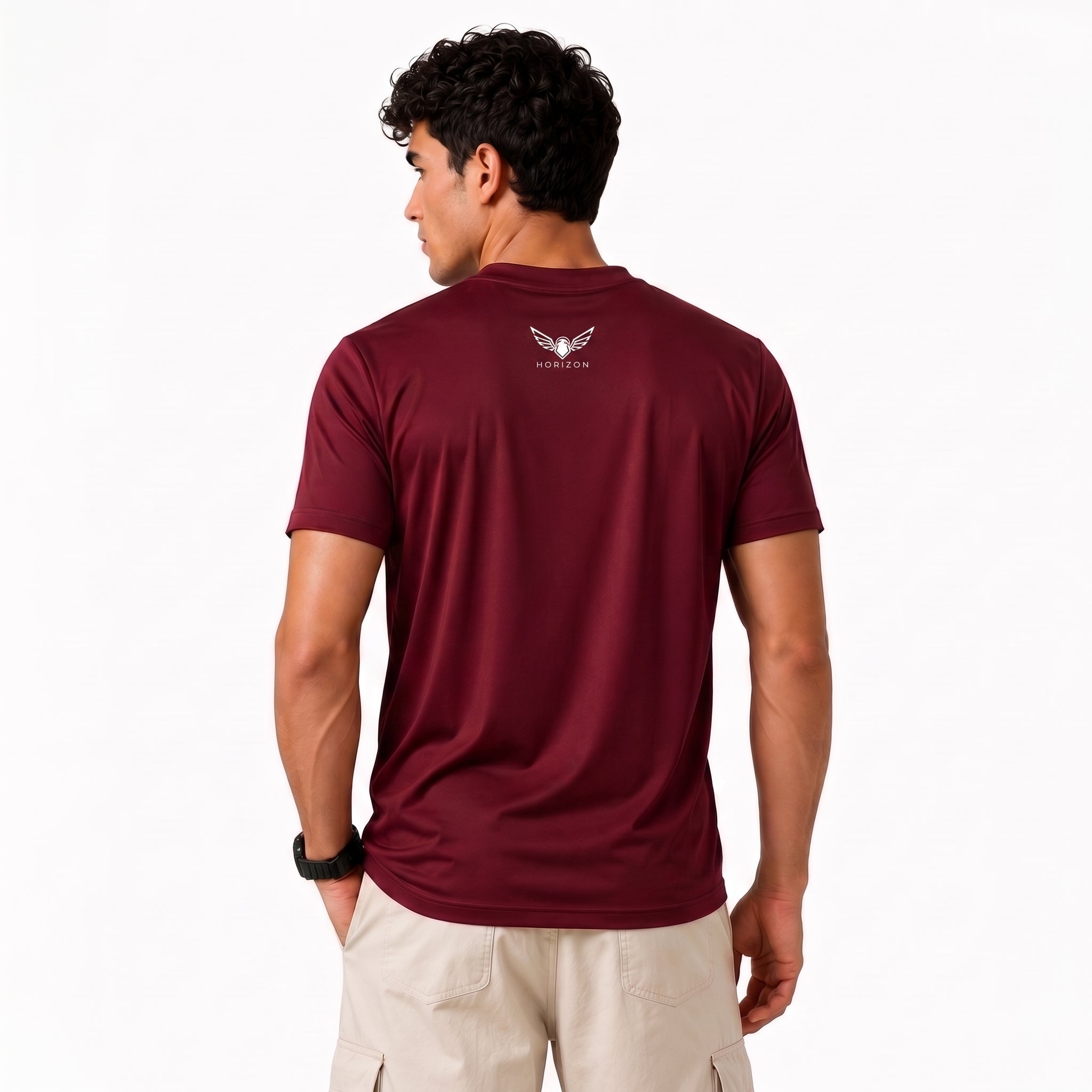 A man viewed from the back wearing a maroon short-sleeve athletic t-shirt with a small white winged logo and the brand name 'VULCAN' printed on the upper back, paired with beige cargo shorts against a plain white background.
