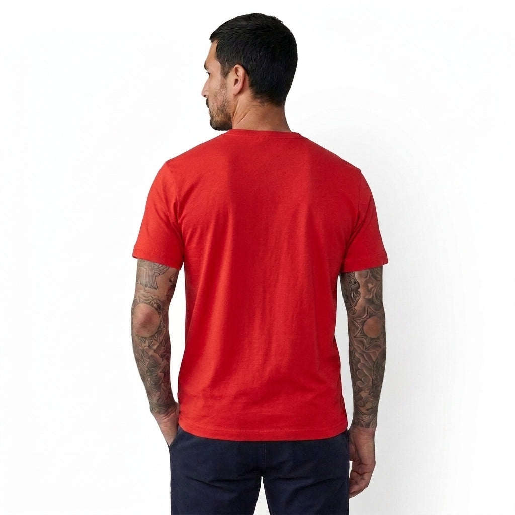 A man with tattoos is shown from the back wearing a bright red short-sleeve t-shirt and dark navy pants against a plain white background.