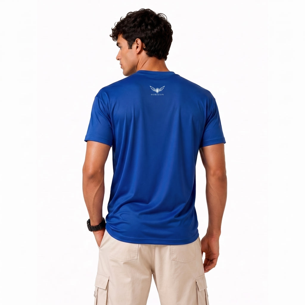 A man wearing a royal blue athletic t-shirt with a small white winged logo on the back, paired with beige cargo pants, shown from a rear three-quarter view against a white background.
